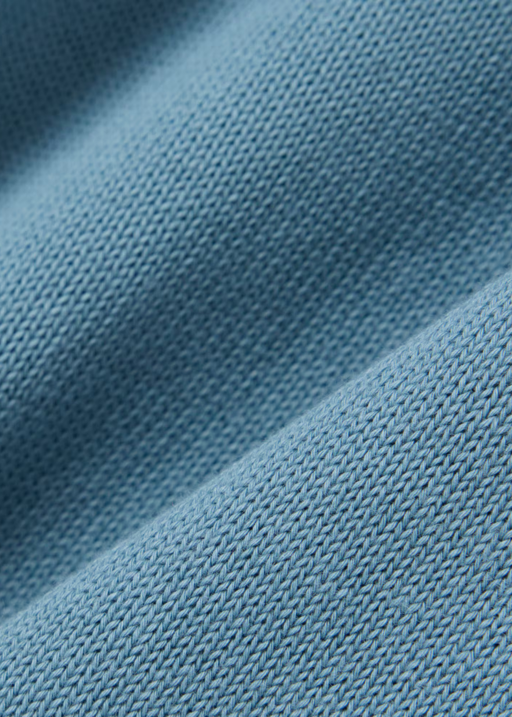 Gros plan sur le tricotage fin en jersey de coton biologique bleu gris du pull Lacoste.
