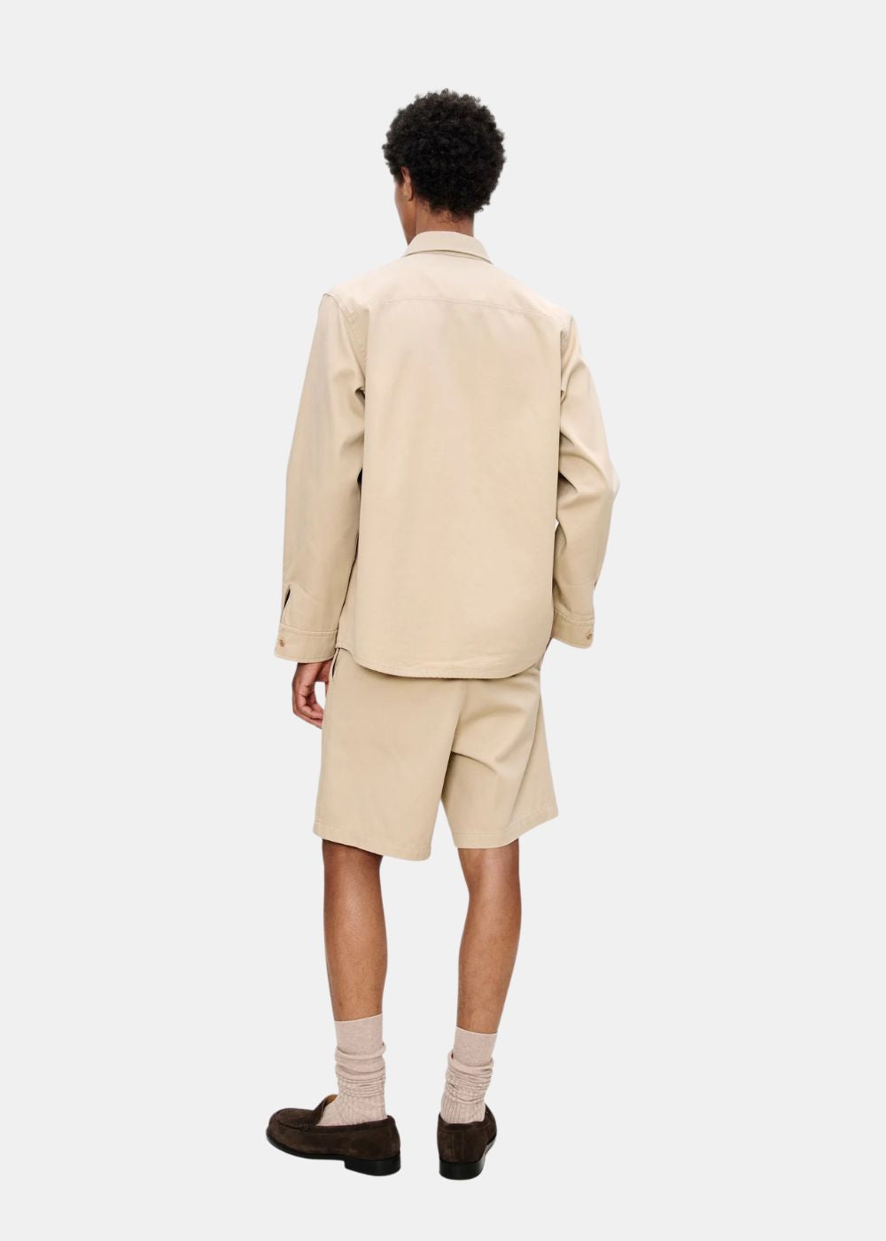 Look complet de dos montrant la coupe droite de la surchemise beige A.P.C. et le short coordonné.