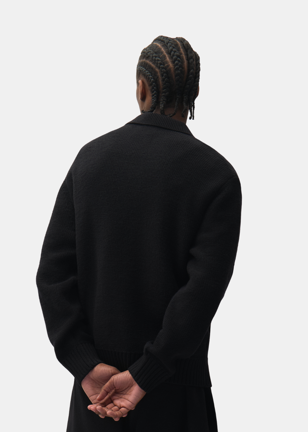 Plan buste de dos d'un mannequin montrant la coupe épurée du cardigan zippé en maille noire Arte-Antwerp.