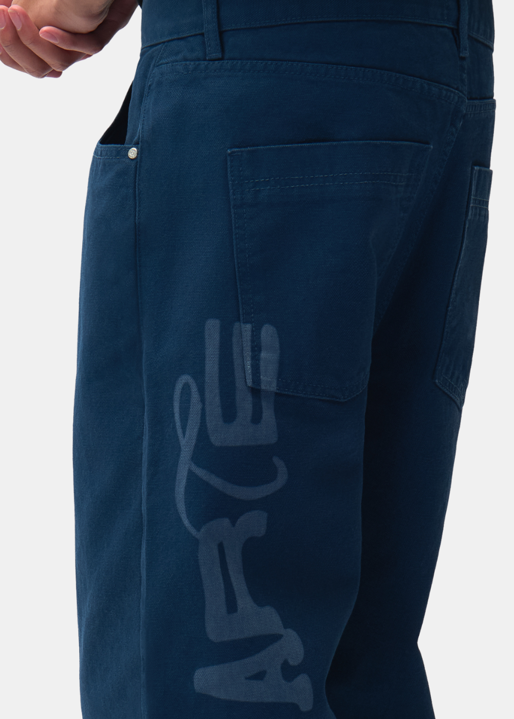Gros plan sur la poche arrière et l'imprimé stencil du logo ARTE le long de la jambe du pantalon marine Arte-Antwerp.