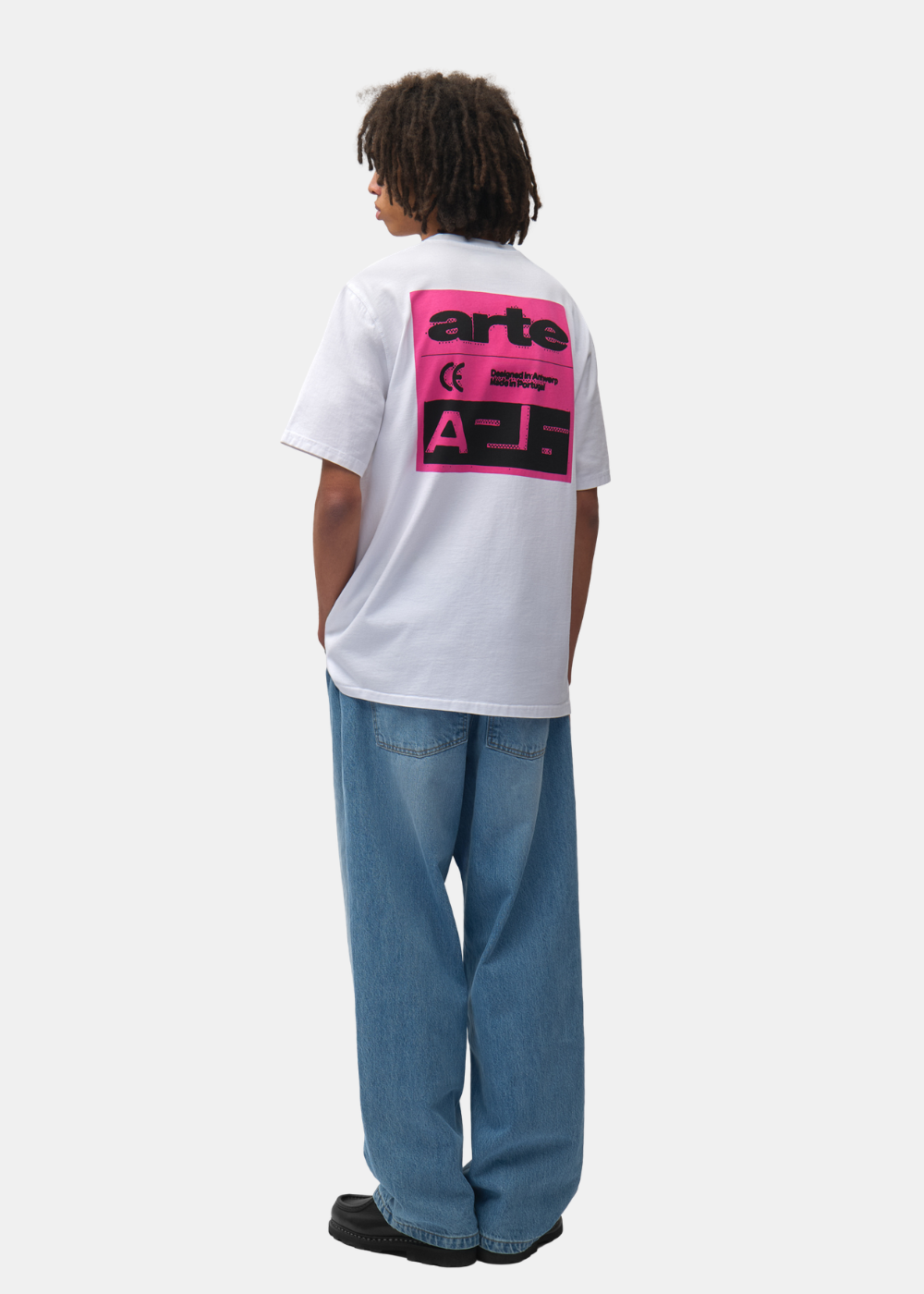 Mannequin de dos portant le t-shirt blanc Arte-Antwerp, un jean bleu et des chaussures noires.