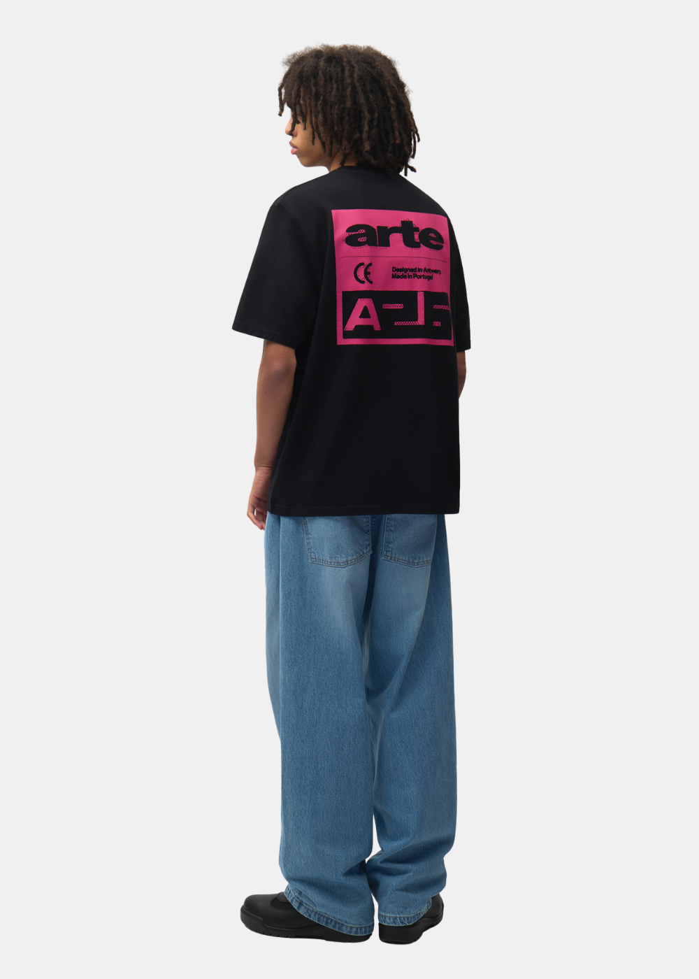 Mannequin de dos portant le t-shirt noir Arte-Antwerp, un jean bleu et des chaussures noires.
