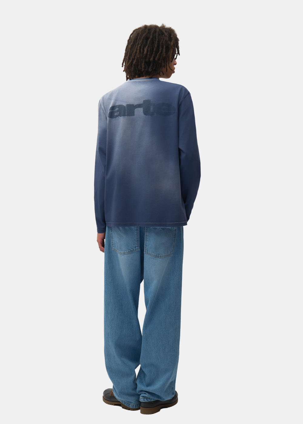 Mannequin de dos portant le t-shirt manches longues bleu marine Arte-Antwerp, un jean bleu et des chaussures sombres.