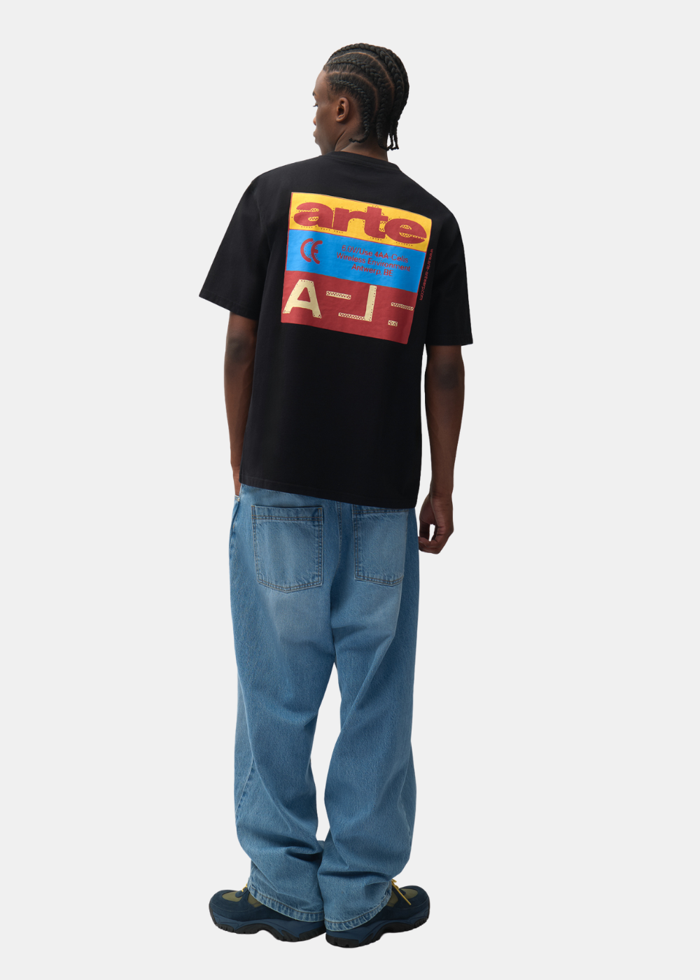 Mannequin de dos portant le t-shirt noir Arte-Antwerp avec graphique, un jean bleu ample et des baskets.