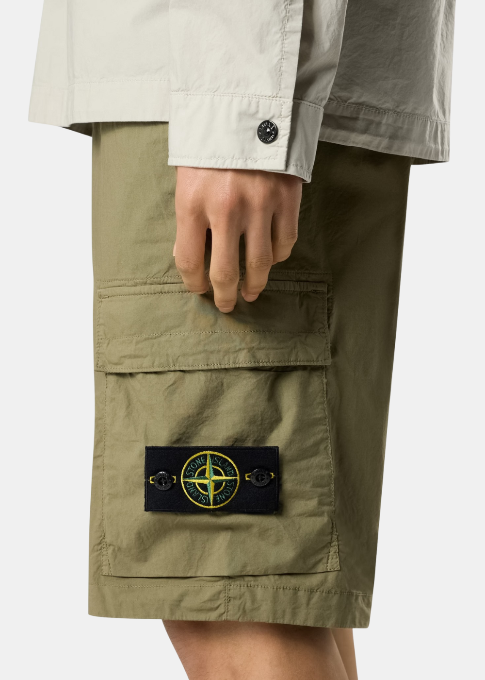 Gros plan sur le patch boussole emblématique Stone Island boutonné sur la poche cargo latérale.