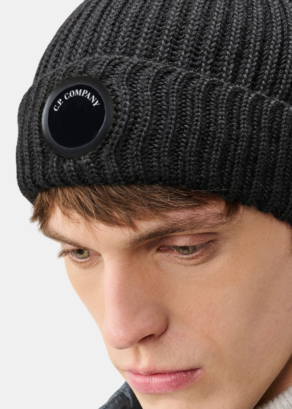 Gros plan sur le détail verre Lens noir C.P. Company incrusté sur le revers du bonnet