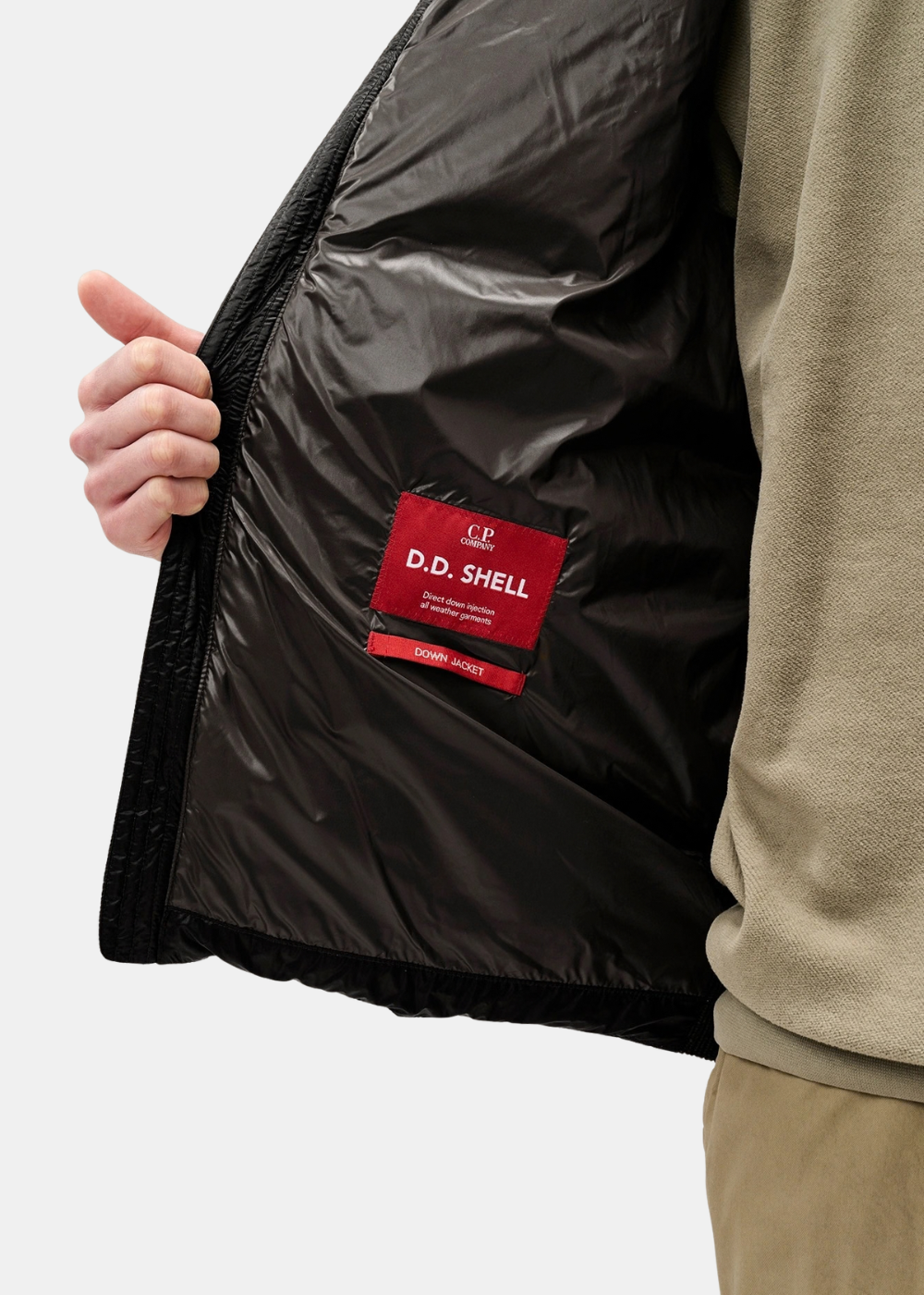 Gros plan sur la doublure intérieure noire et l'étiquette rouge D.D. Shell du cardigan C.P. Company