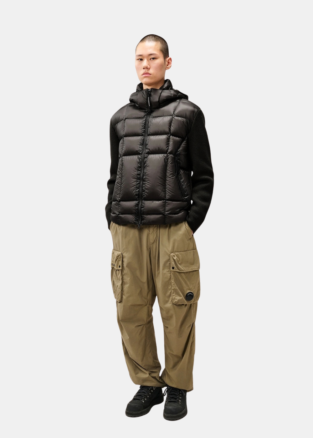 Silhouette complète portée du cardigan C.P. Company noir avec pantalon cargo beige et bottines