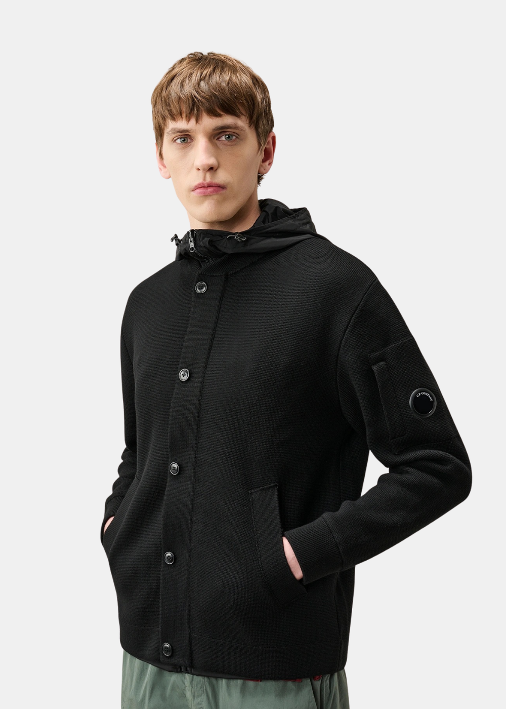 Mannequin homme vu de demi-corps de face portant le cardigan boutonné C.P. Company noir côté maille, les mains dans les poches