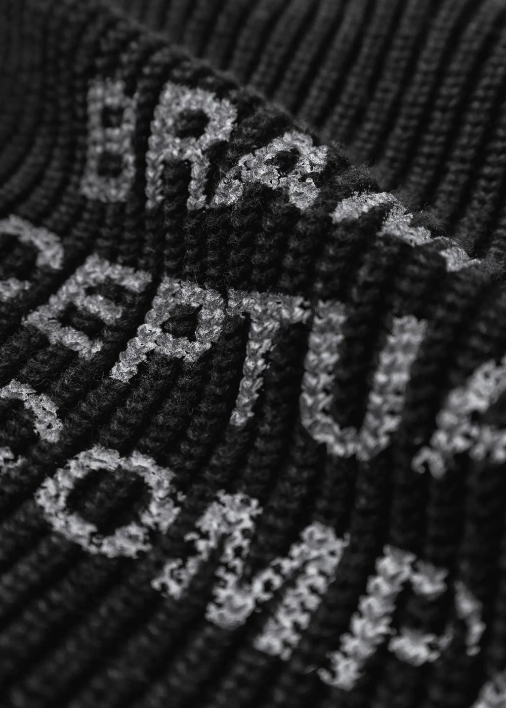 Gros plan sur la maille côtelée noire du cardigan Bram's Fruit et le lettrage imprimé en relief   