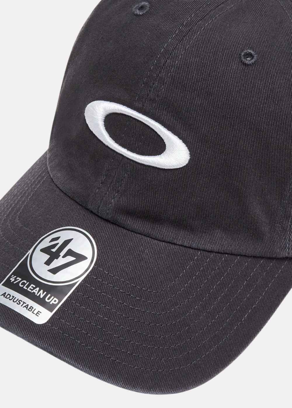 Gros plan sur la broderie du logo Ellipse Oakley blanc et le sticker '47 Clean Up sur la visière