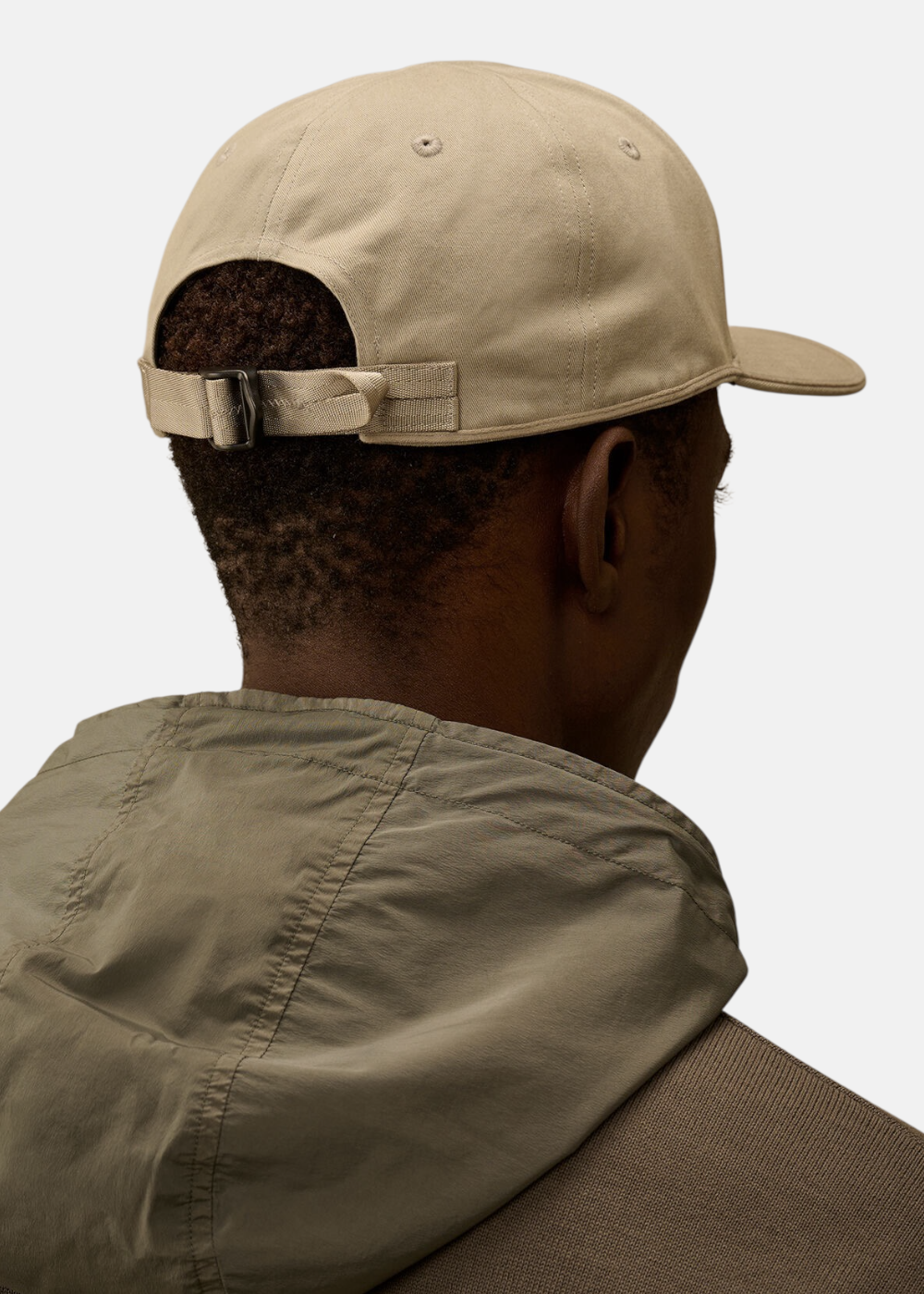 Vue arrière en gros plan de la casquette beige C.P. Company avec sa sangle de réglage et boucle en métal