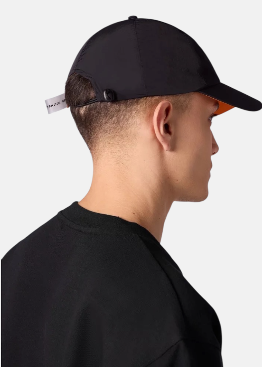 Homme portant une casquette Gertrude Jaron en nylon noir vue de dos avec lien de serrage et étiquette blanche