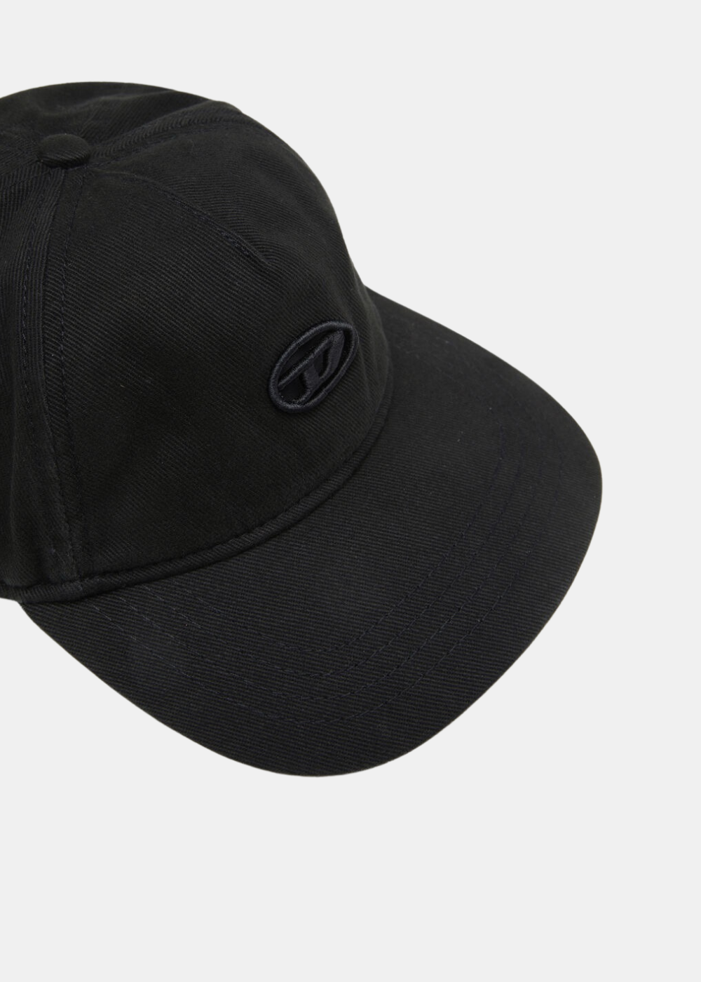 Gros plan en plongée sur l'avant de la casquette noire Diesel, mettant en valeur le logo Oval D brodé ton sur ton