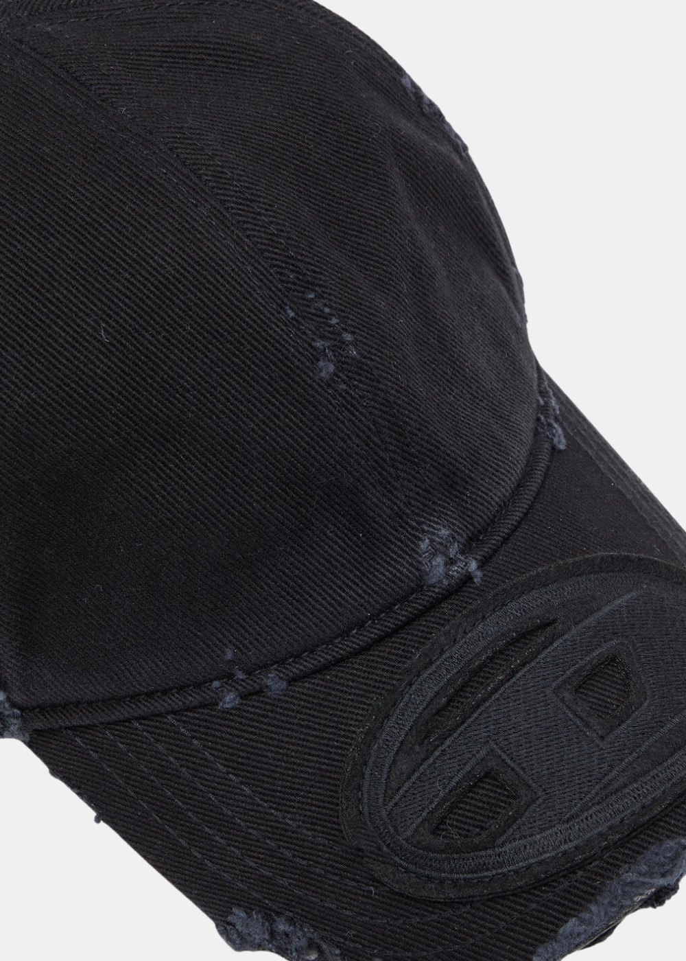 Gros plan sur la visière de la casquette noire Diesel mettant en valeur le logo Oval D brodé et la texture effet usé.