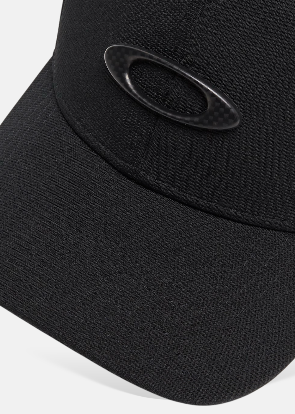 Gros plan sur le logo ellipse en métal noir de la casquette Oakley Tincan montrant la finition et la texture
