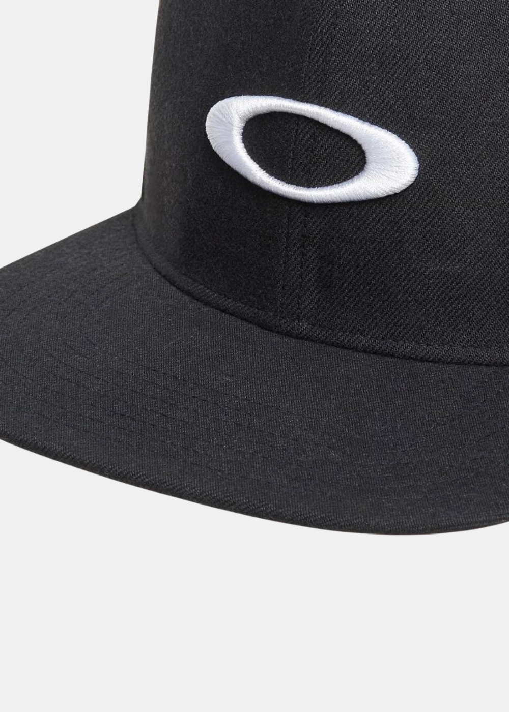 Gros plan sur le logo Ellipse Oakley blanc brodé sur la couronne noire de la casquette