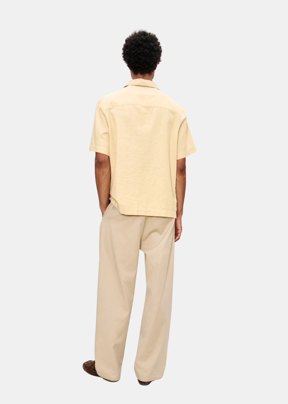 Vue de dos de la chemise A.P.C. Jude beige à manches courtes portée par un mannequin avec un pantalon large.