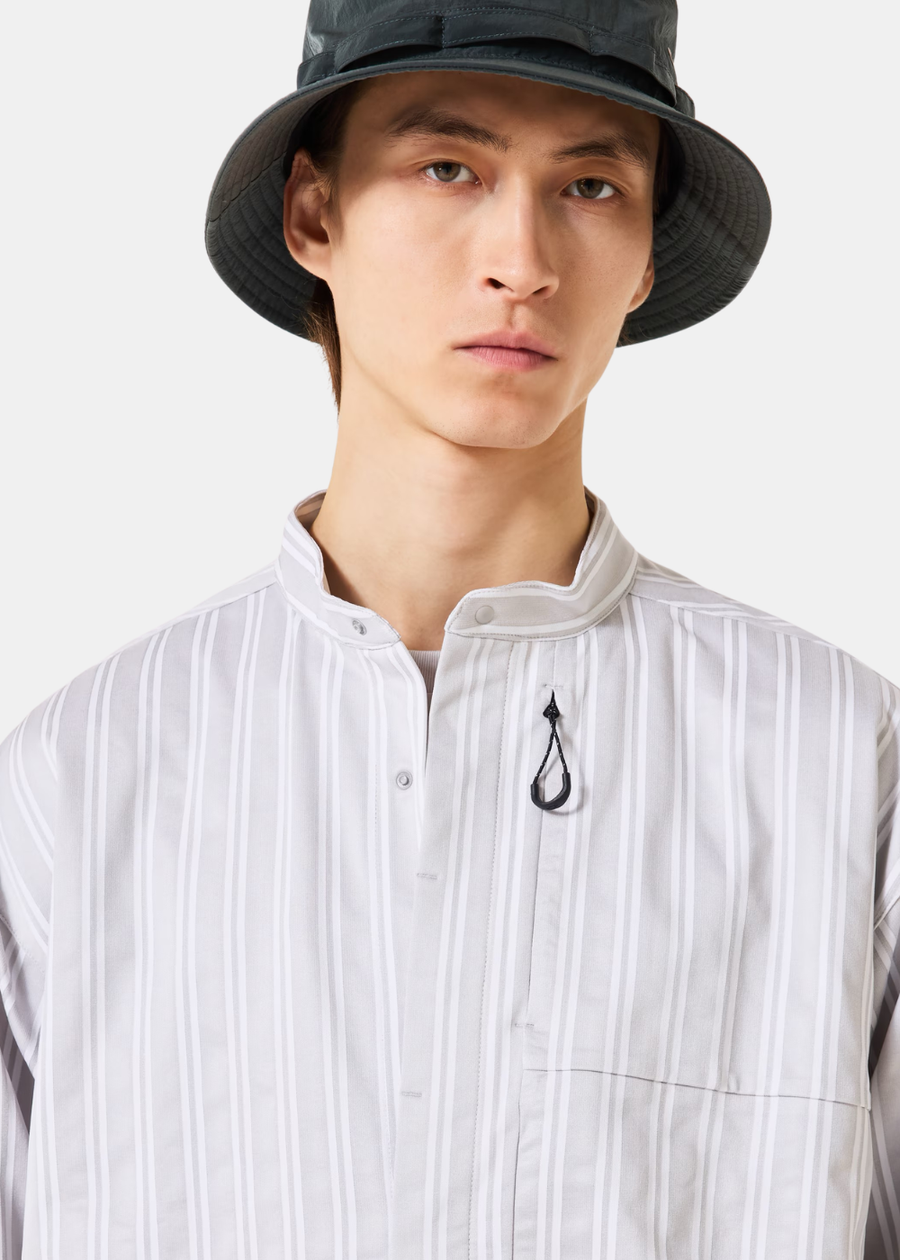 Zoom sur le buste du mannequin portant la chemise Oakley blanche, soulignant le col officier et le cordon de serrage.