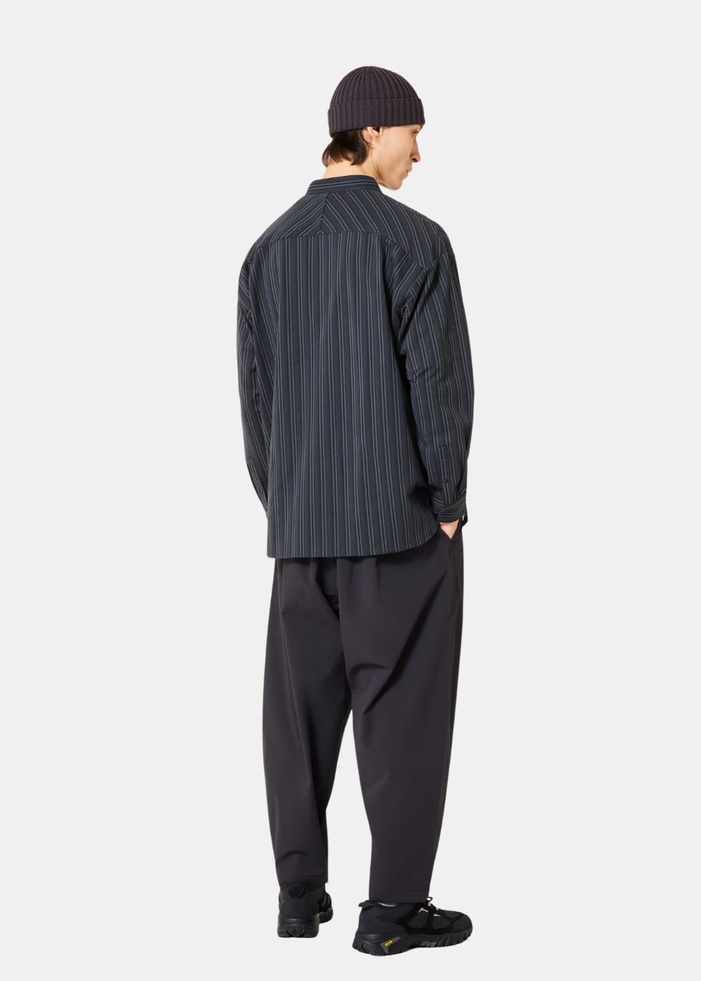 Mannequin de dos portant la chemise Oakley grise à rayures verticales et un pantalon ample noir.