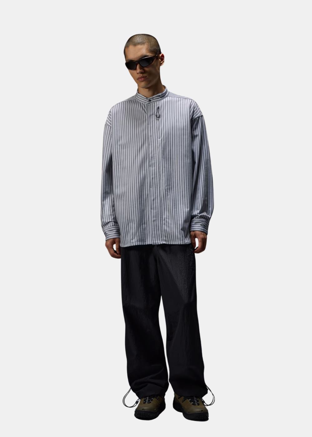 Mannequin portant la chemise à manches longues Oakley FGL Fuel blanche rayée avec lunettes de soleil et pantalon ample noir