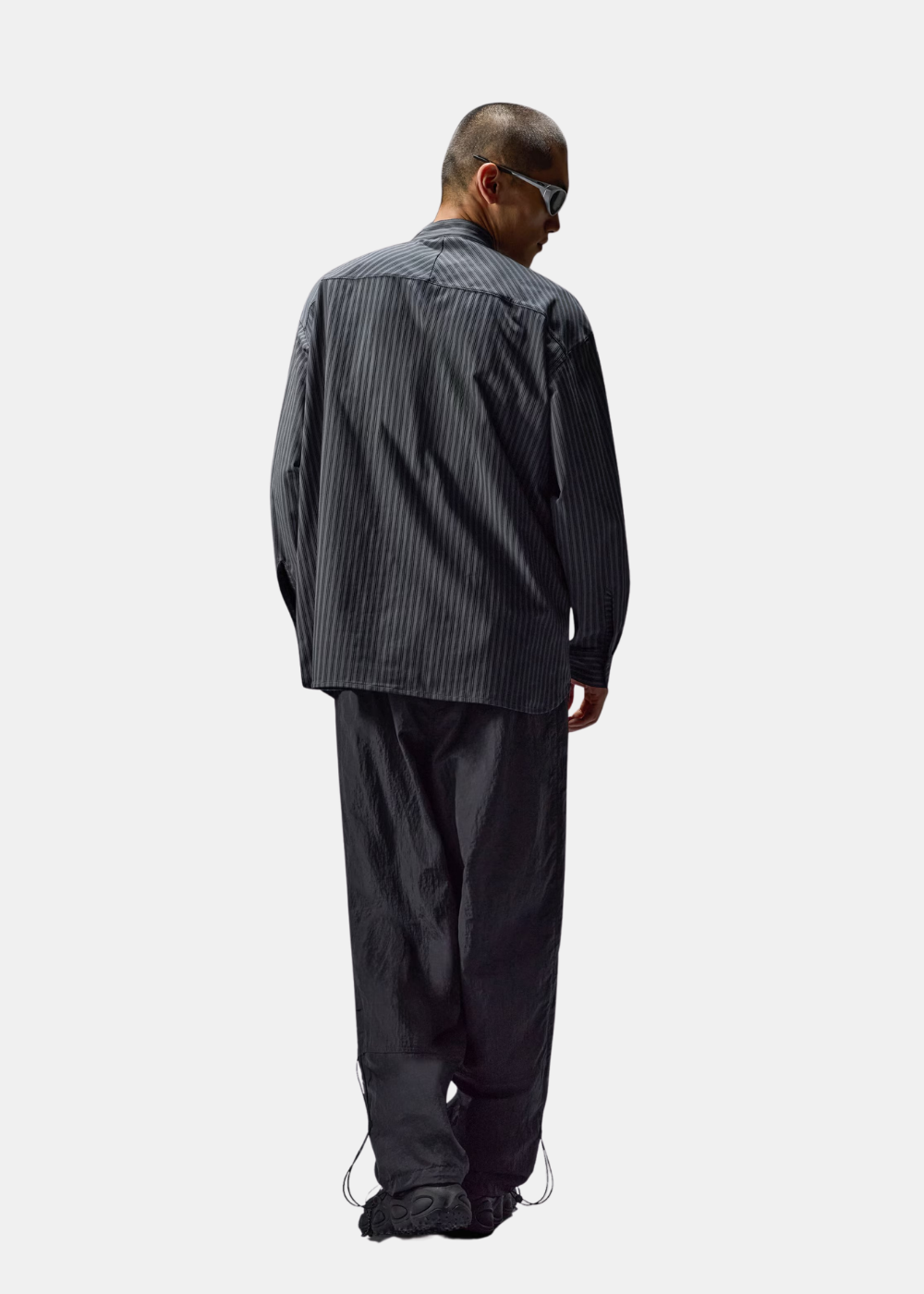 Vue de dos du mannequin portant la chemise technique Oakley FGL Fuel grise rayée et pantalon ample