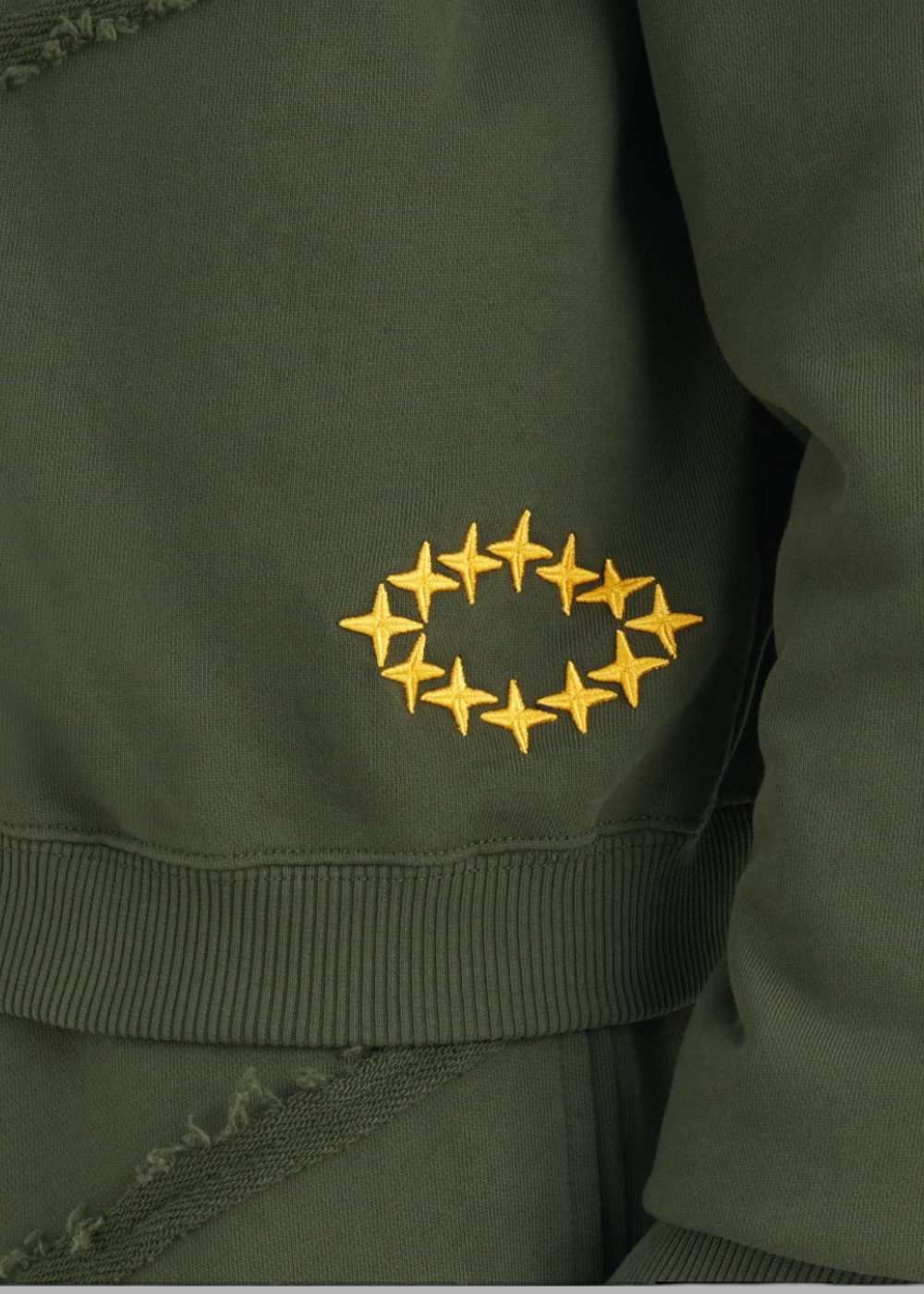 photo zoomée sur les détails du Sweat à capuche Zippé Études Studio vert forêt. Cette photo mets en avant les détails de broderie du sweat études