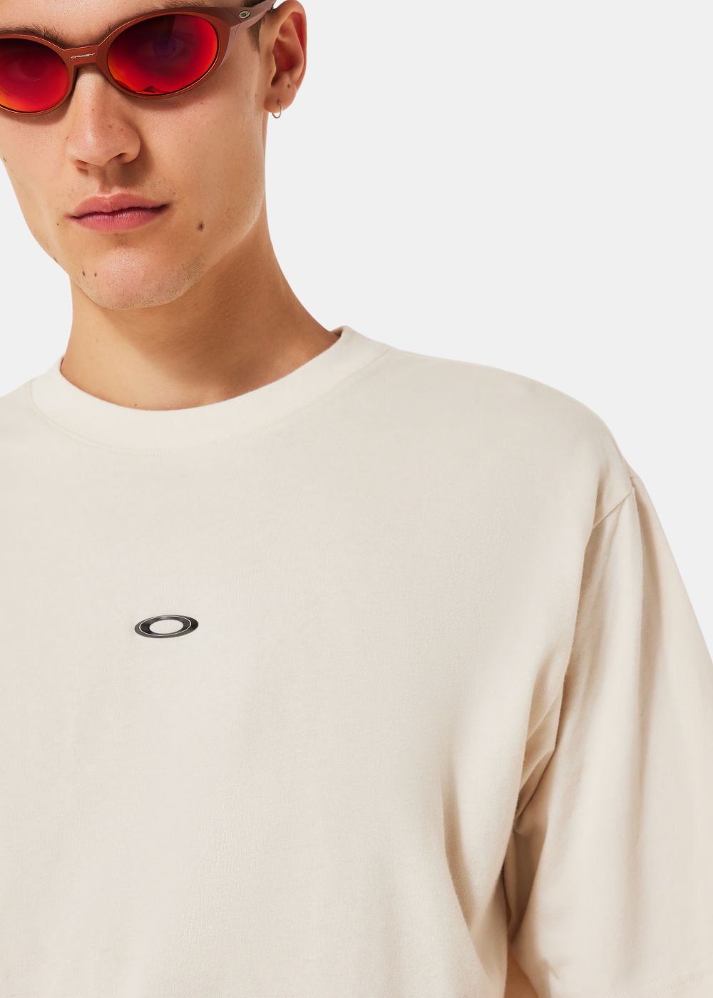 Gros plan sur le logo Oakley Ellipse argenté sur le tissu en coton beige.