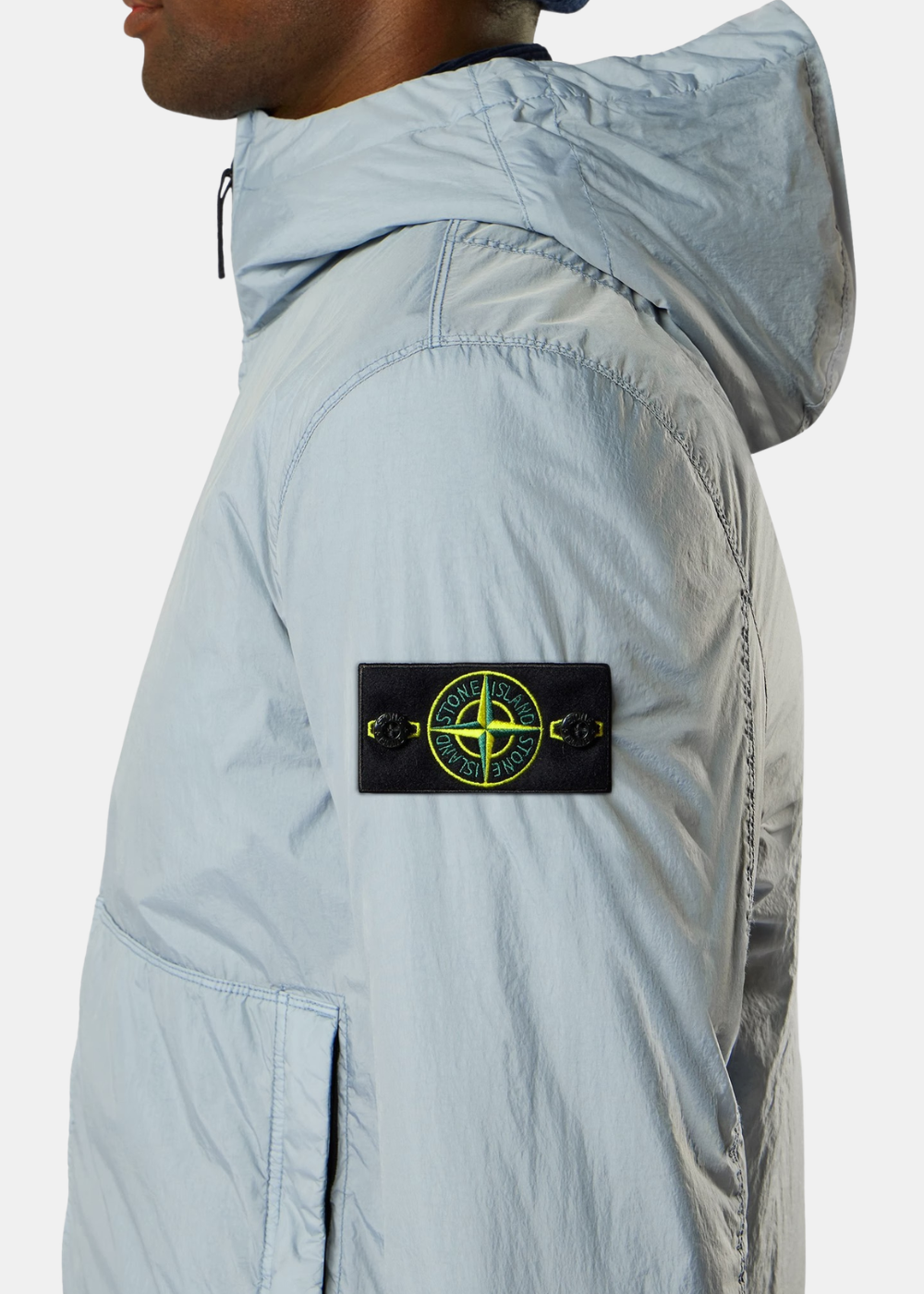 Gros plan de profil sur le bras gauche du bomber gris porté (10_4.jpg), mettant en valeur le badge boussole emblématique Stone Island boutonné sur la matière plissée Crinkle Reps.