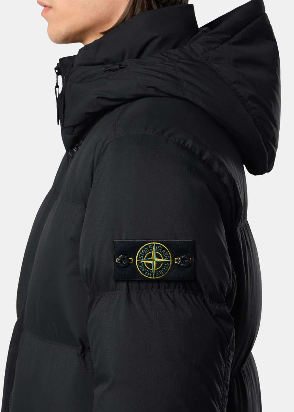 Gros plan sur le bras gauche de la doudoune noire (2.jpg), affichant le badge boussole emblématique Stone Island boutonné sur la texture CORDURA®.