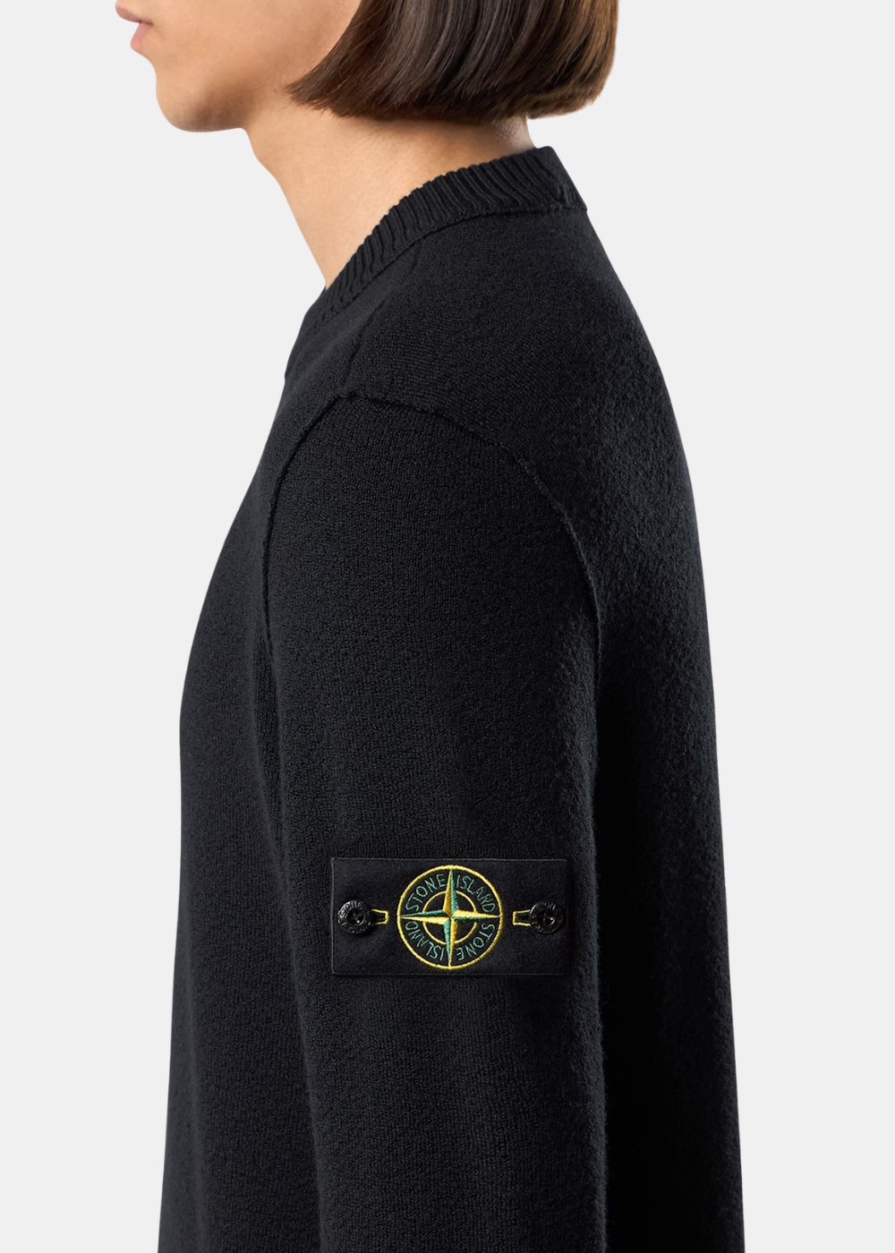 Gros plan de profil sur le bras gauche du pull noir porté (13.jpg), mettant en valeur le badge boussole emblématique de Stone Island et la maille fine.