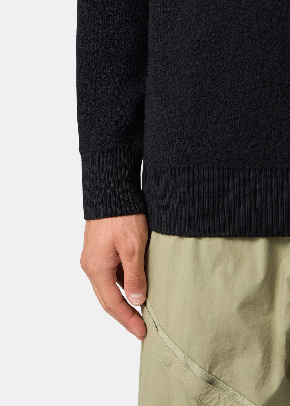 Gros plan sur le bas du pull noir porté (14.jpg), illustrant la texture de la pure laine RWS et les finitions en bord-côte du poignet et de la taille.