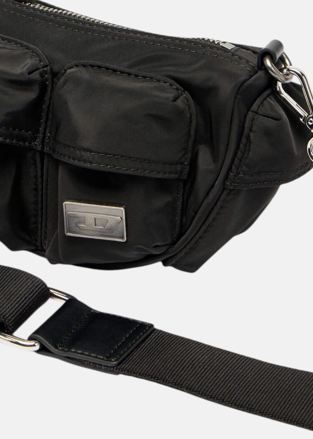Focus sur les poches à rabat, le logo "D" argenté et les attaches de la bandoulière.