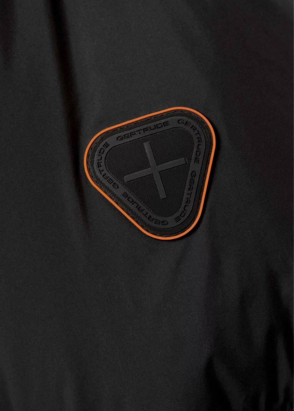 Gros plan sur le patch en silicone gravé du logo Gertrude sur la manche de la doudoune