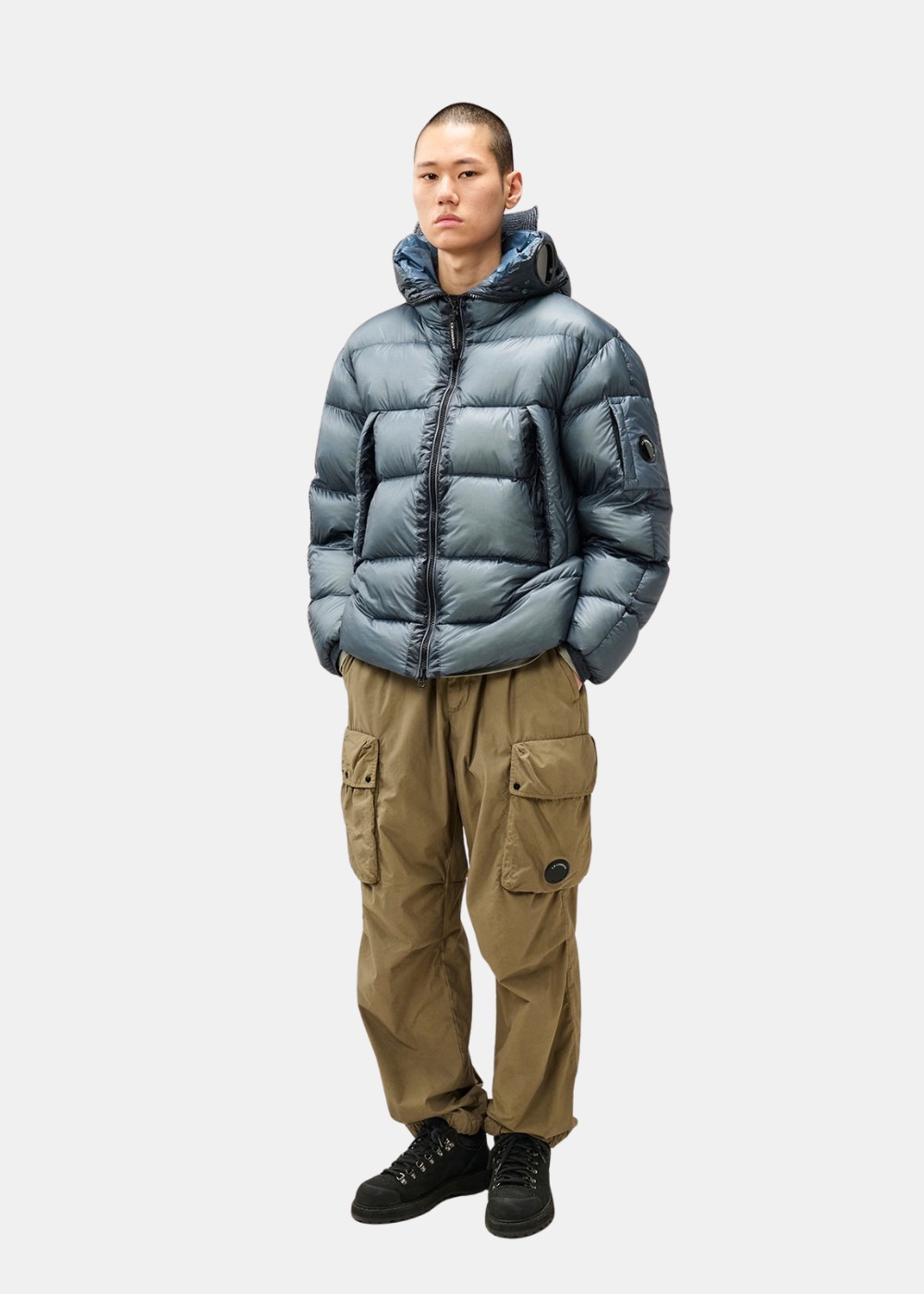 Silhouette complète portée de la doudoune bleu C.P. Company D.D. Shell Explorer avec pantalon cargo beige et chaussures noires
