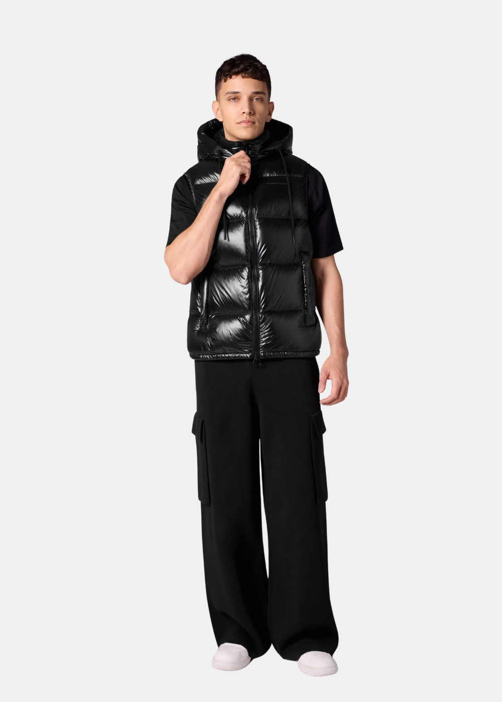 Homme portant la doudoune sans manches Gertrude Cesar noire avec un pantalon cargo large et un t-shirt noir.