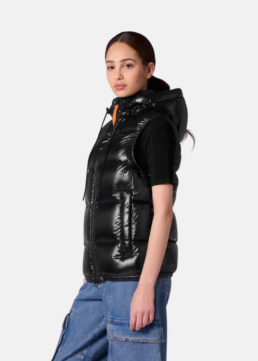 Femme portant la doudoune sans manches Gertrude Cesar noire de profil, mettant en avant la capuche et le zip orange.