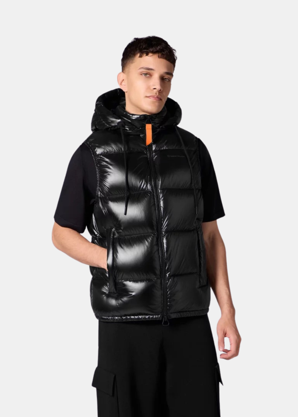 Homme portant la doudoune sans manches Gertrude Cesar noire de face, mettant en avant la capuche et le zip orange.