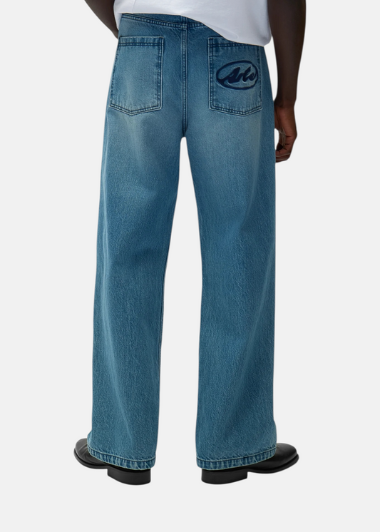 Focus sur l'arrière du jean bleu clair Arte Antwerp porté, montrant le logo brodé sur la poche.