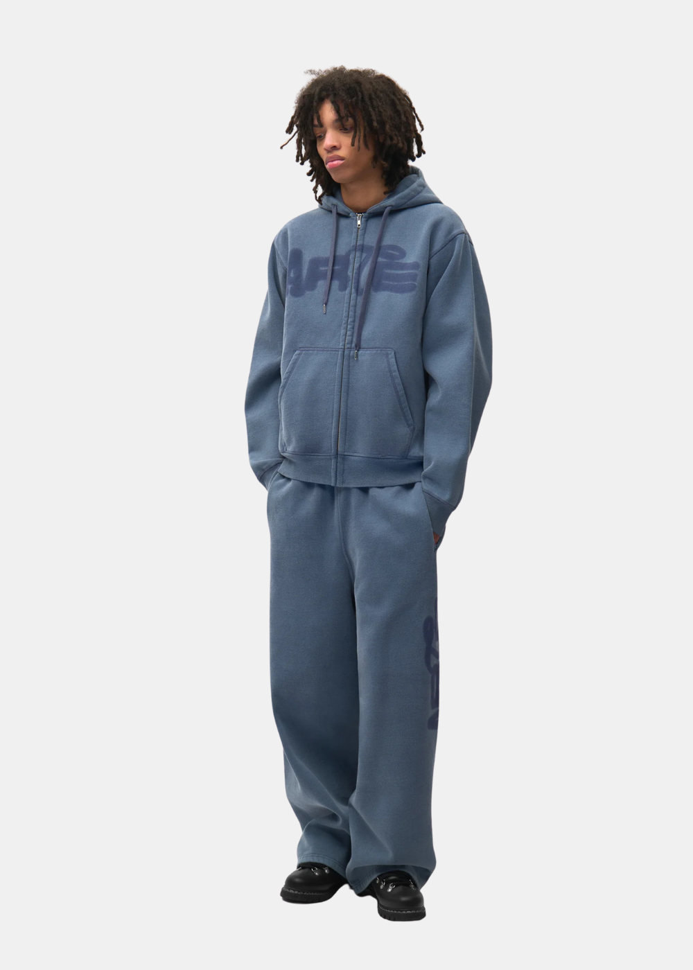 Mannequin homme portant le total look tracksuit bleu délavé Arte Antwerp avec sweat à capuche et jogging ample.