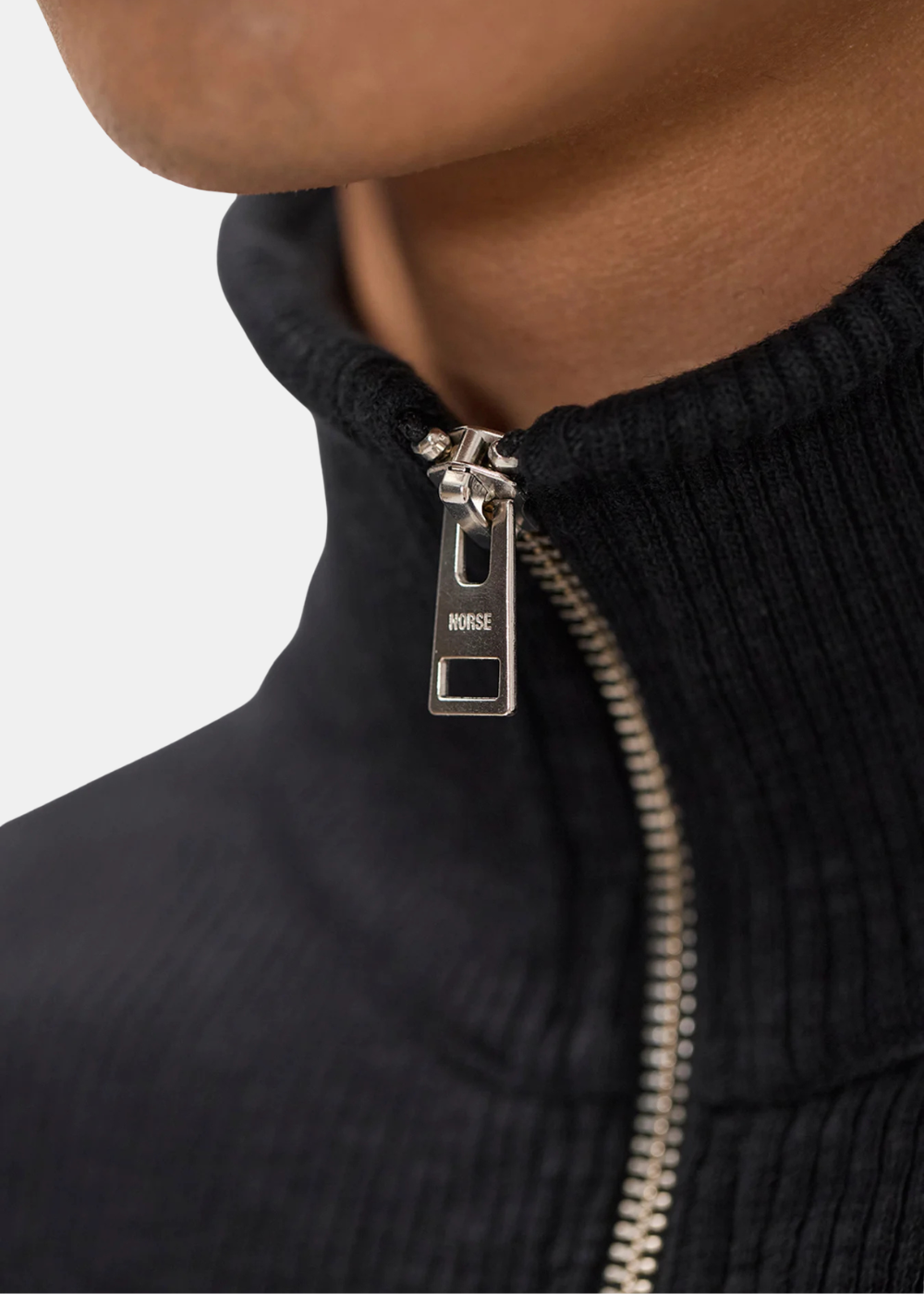 Zoom sur le double curseur métallique gravé Norse du gilet Homme noir en maille côtelée.