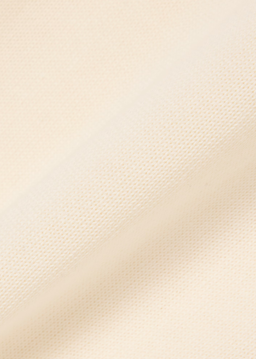 Gros plan sur le tricotage fin en jersey de coton biologique crème du pull Lacoste.