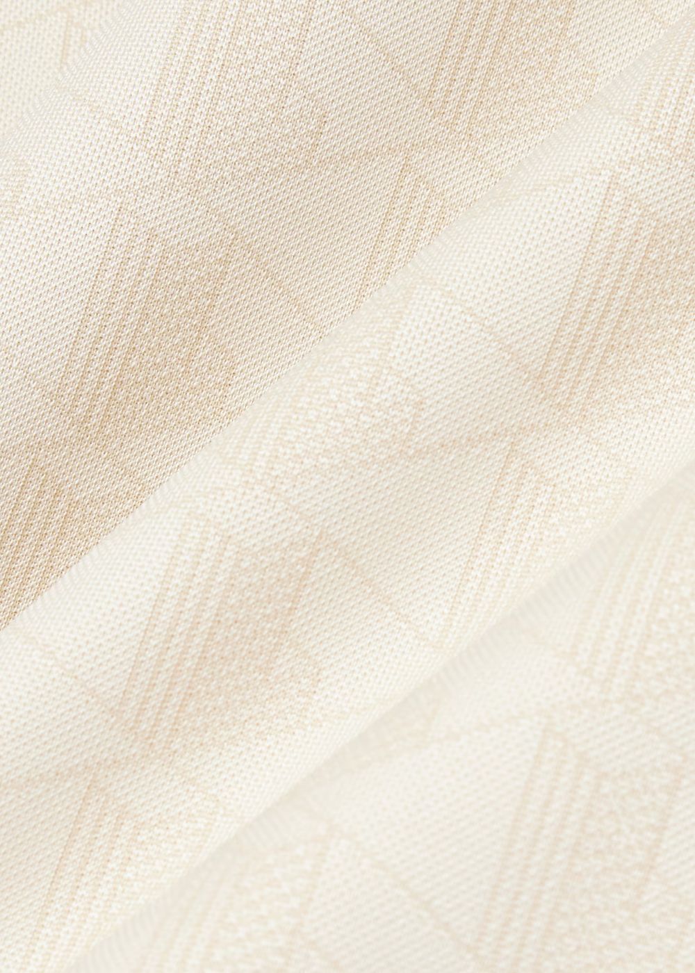 Gros plan sur la texture en maille jacquard au motif monogramme ton sur ton du t-shirt Lacoste.