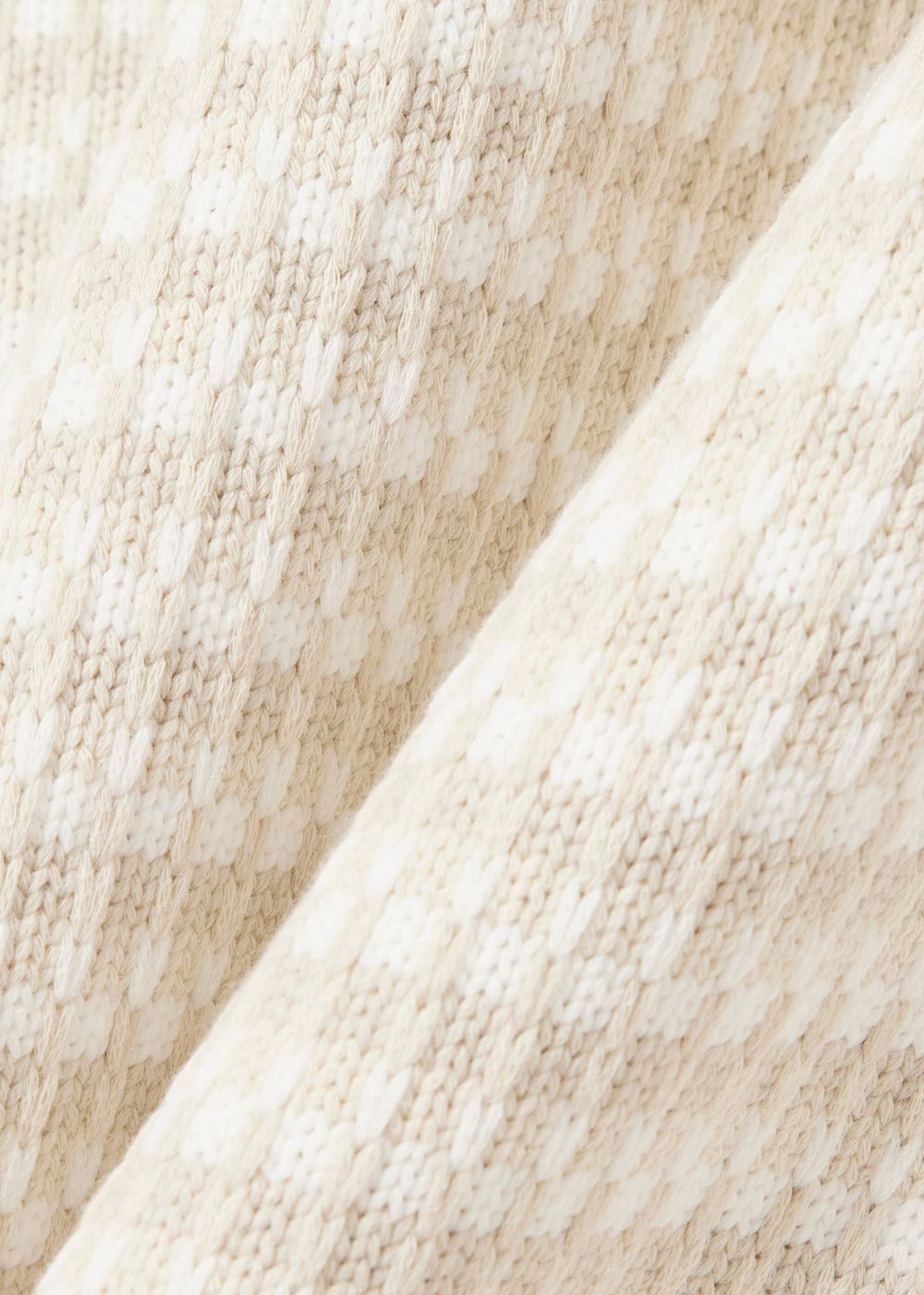 Gros plan sur la texture en relief de la maille point fantaisie en coton biologique du pull Lacoste.
