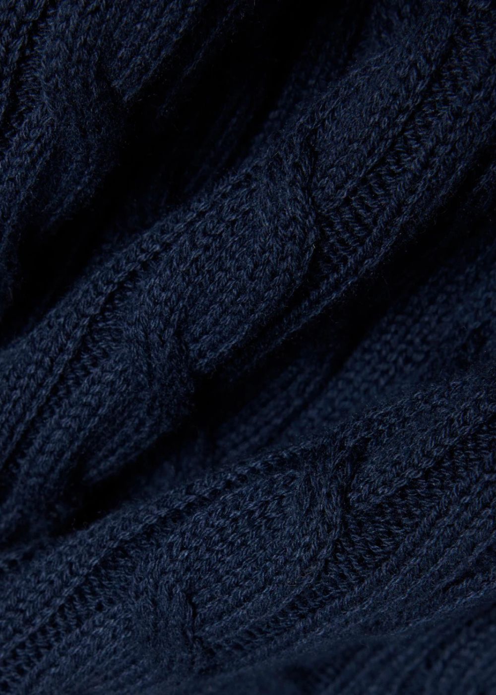 Gros plan sur le relief du tricotage en maille torsadée du polo Lacoste bleu marine.
