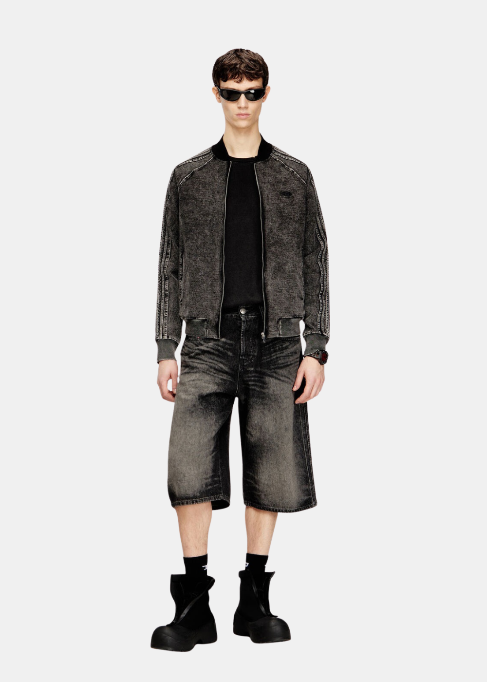 Look complet homme avec veste zippée, t-shirt noir et bermuda long en denim gris délavé.