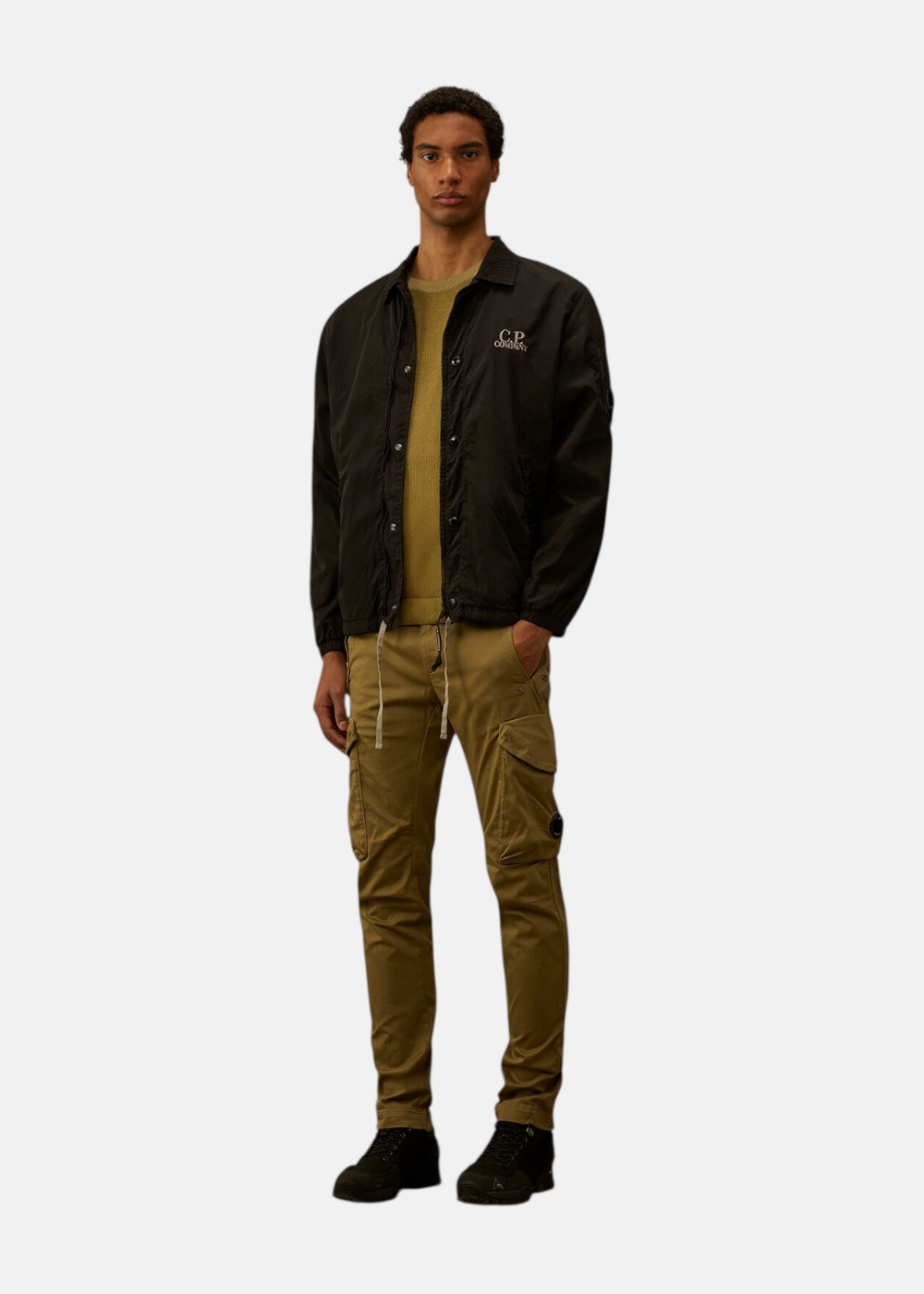 Mannequin portant une surchemise noire C.P. Company sur un pull olive et un pantalon cargo kaki.