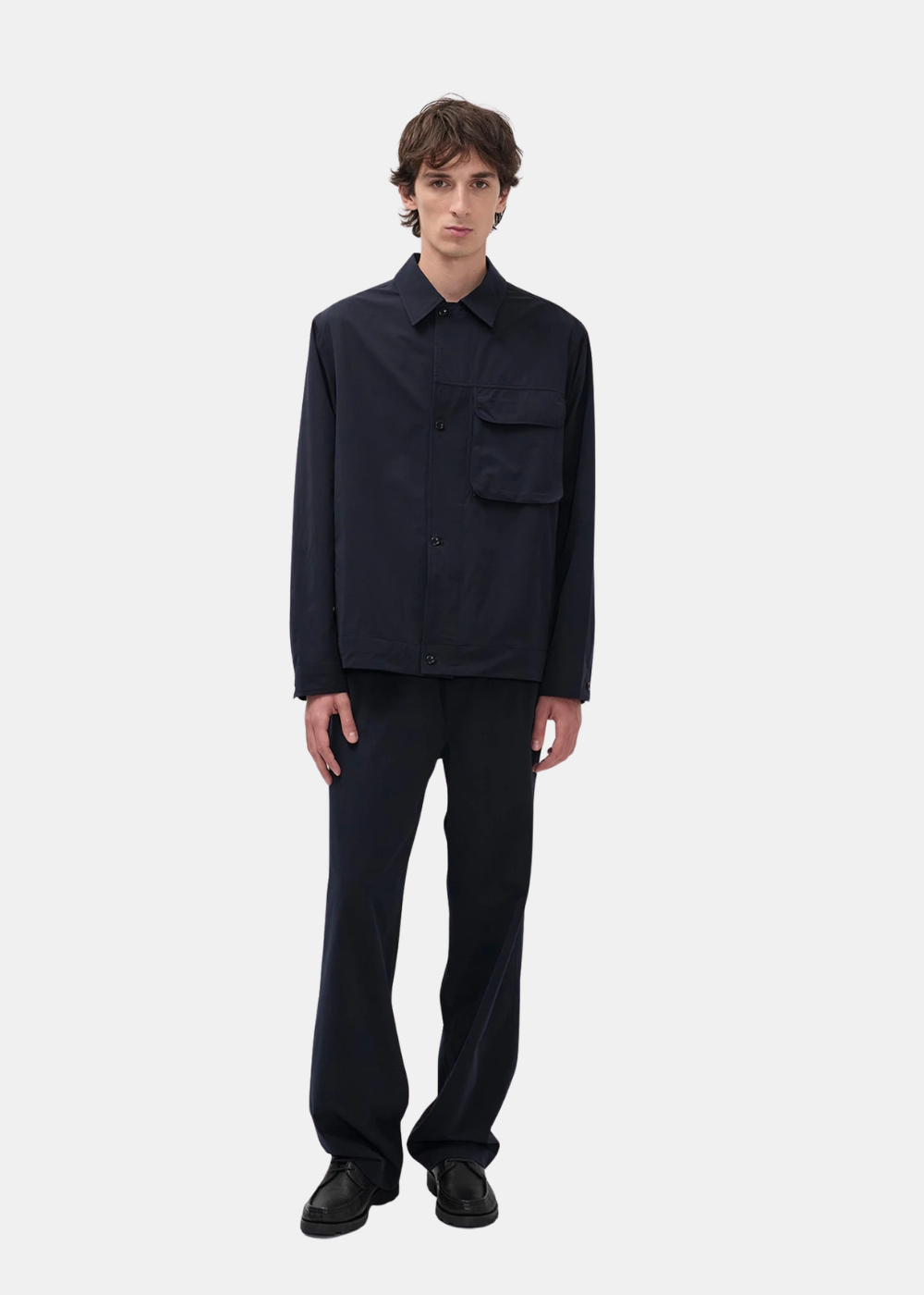 Un mannequin homme porte l'ensemble technique bleu marine Norse Projects avec veste et pantalon assortis.