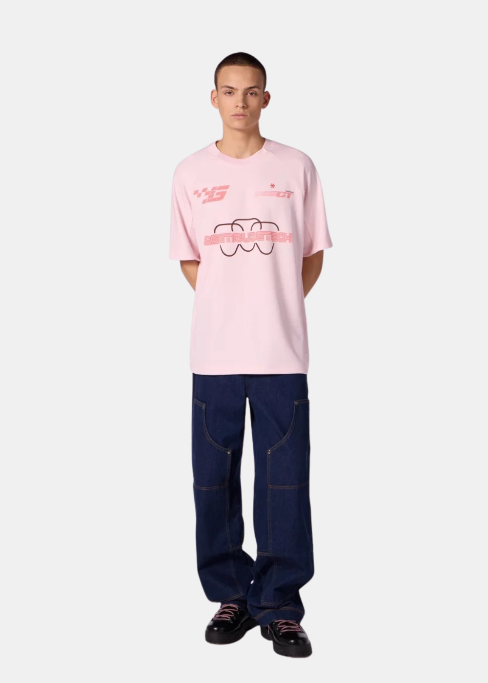 Un mannequin porte le t-shirt baseball rose Gertrude Baris avec un jean large bleu foncé et des chaussures noires.