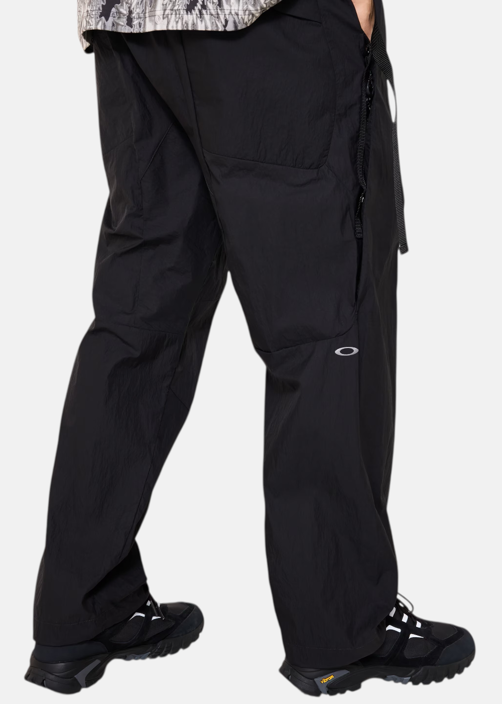 Vue de dos des jambes du pantalon noir Oakley montrant la coupe ample et le petit logo blanc sur le mollet gauche